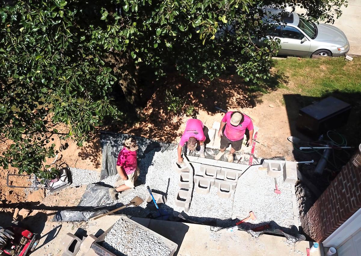 The crew setting retaining wall block on a gravel base.