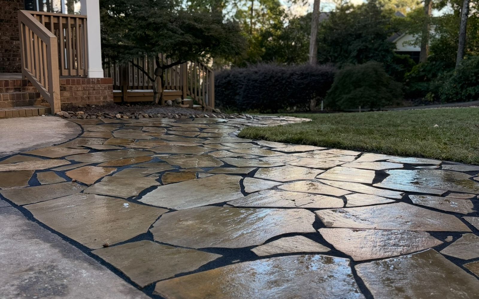 A finished flagstone patio and walkway laid against a concrete driveway at a home in the Upstate.