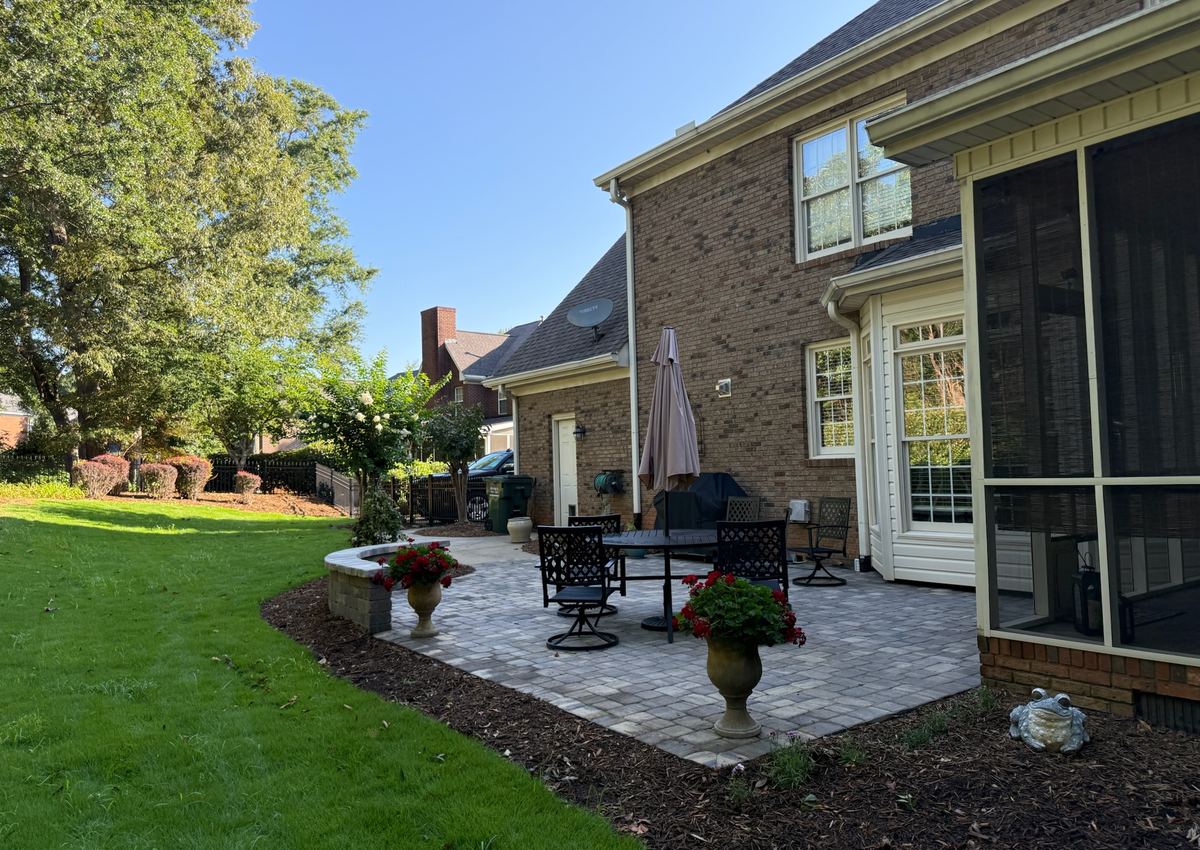 A paver patio with outdoor furniture beside a maintained back lawn.
