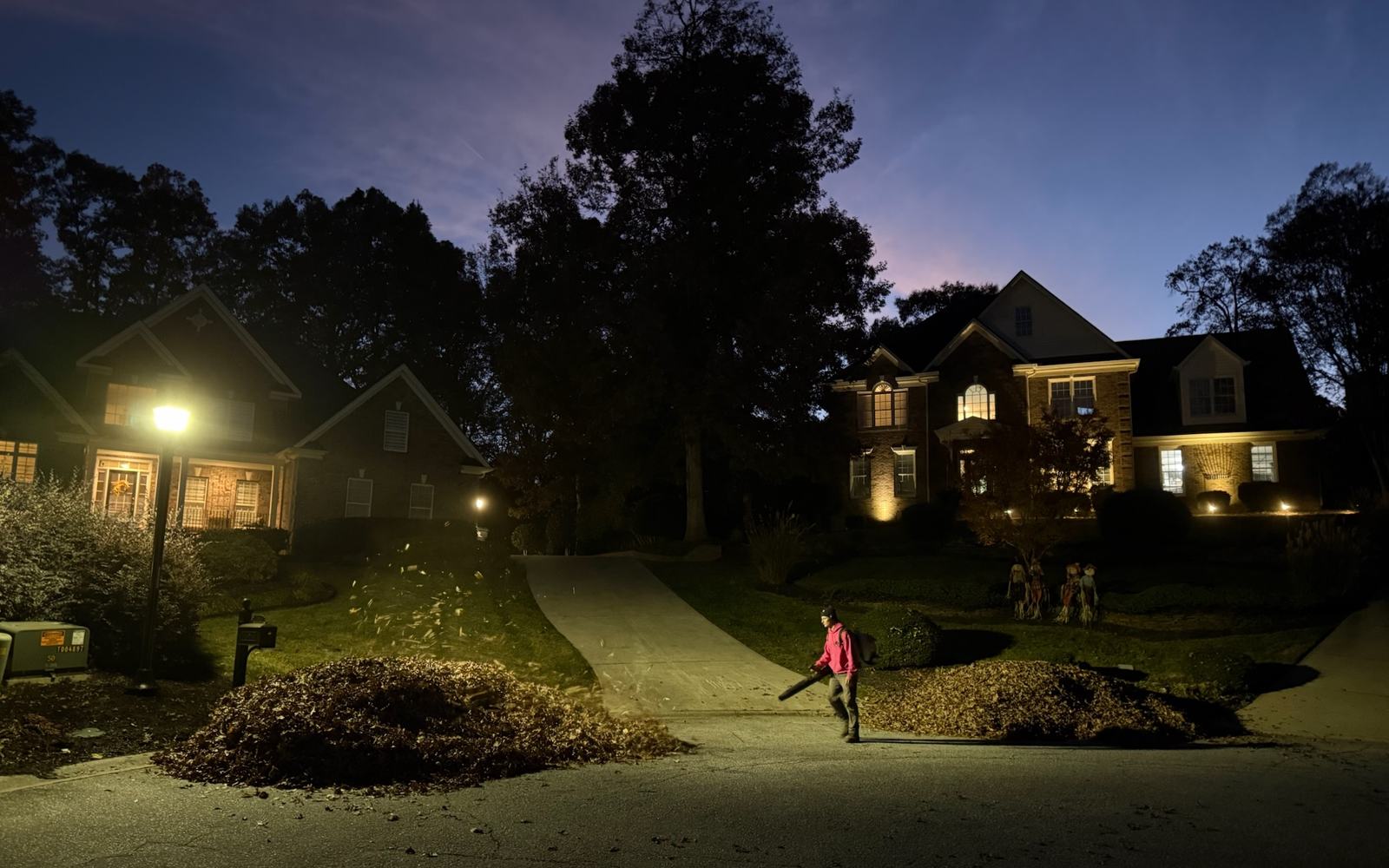 A home and its landscaping lit at dusk by landscape lighting.