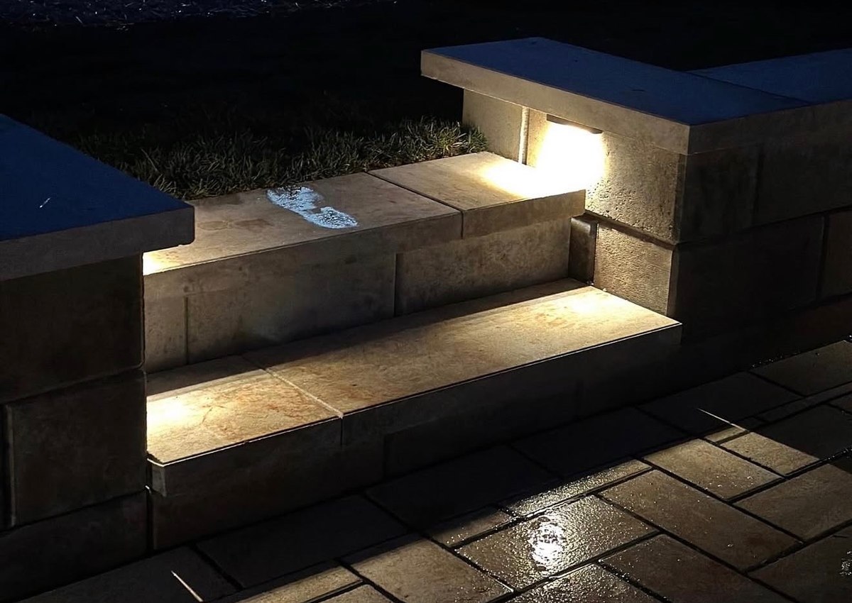 Recessed lights washing down a flight of paver steps after dark.