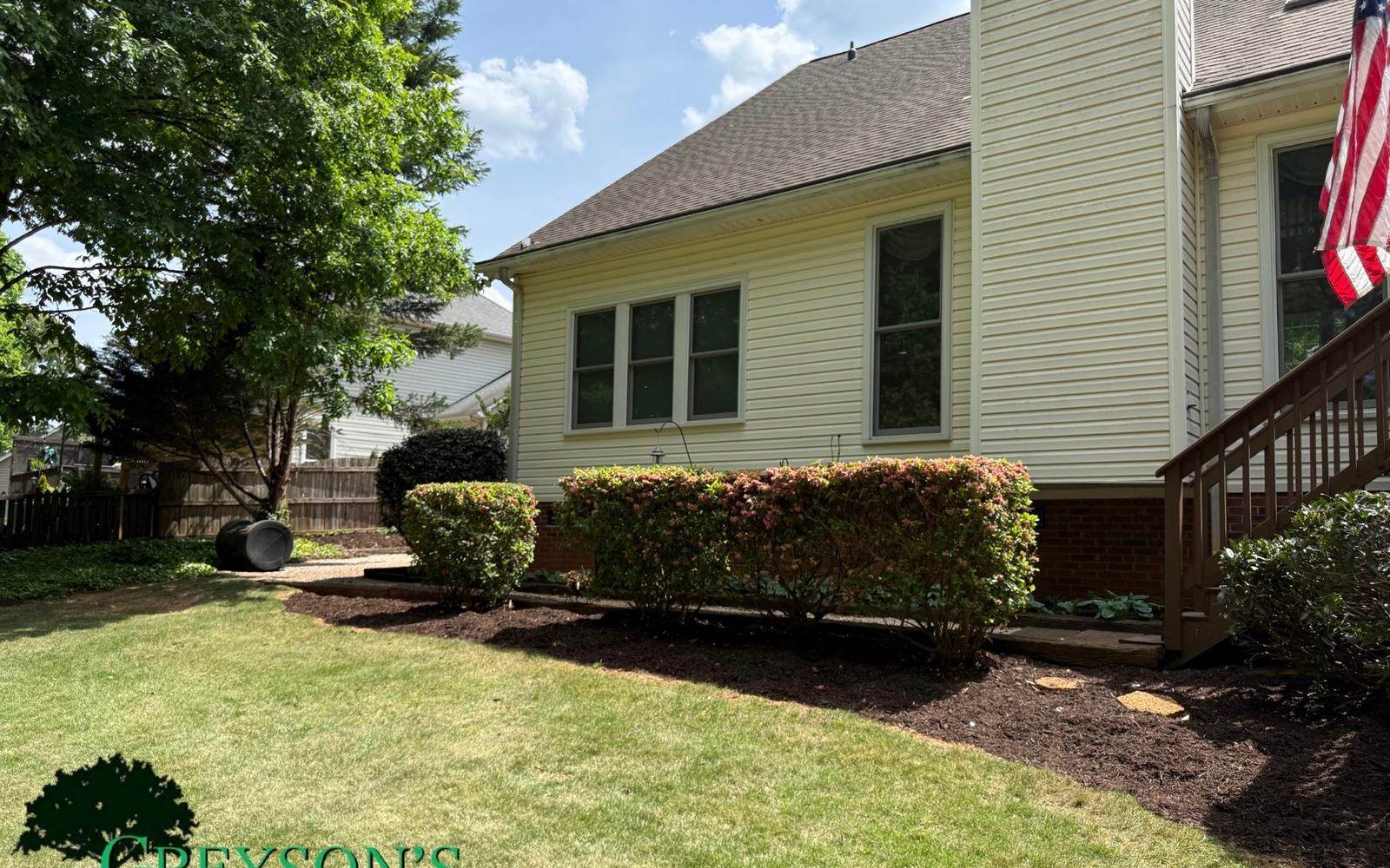 A sweeping mulch bed curve cut into a lawn beside a house.