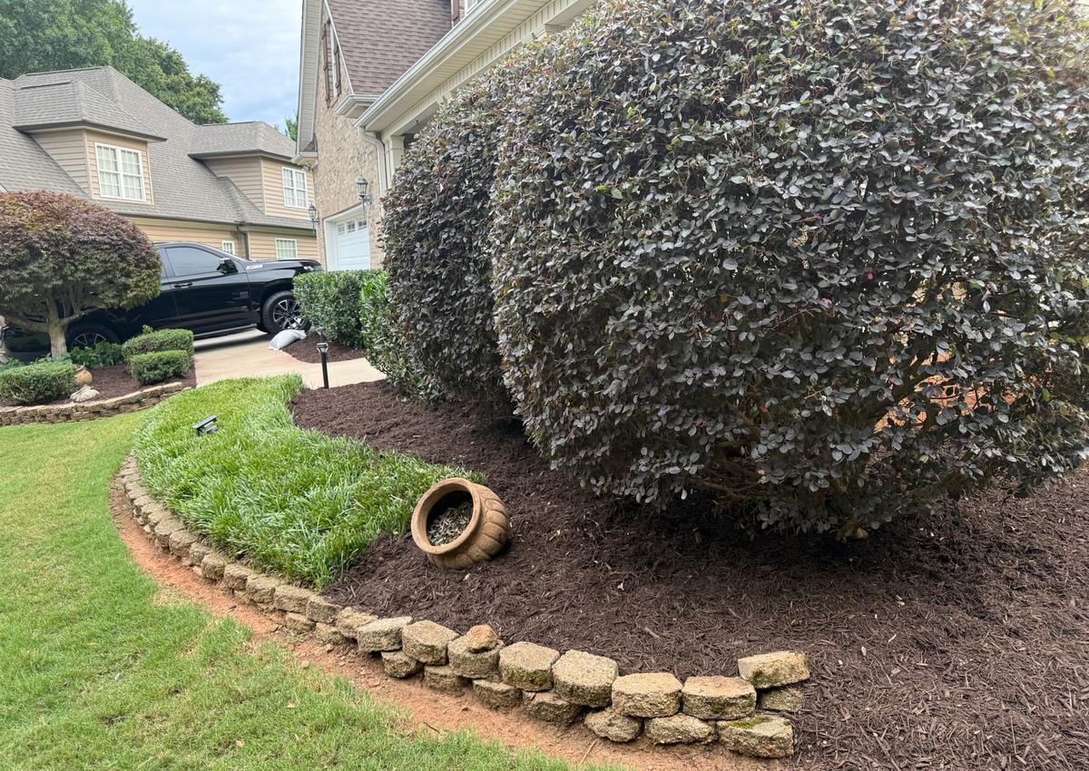 A mulched bed edged with a natural stone border alongside a lawn.