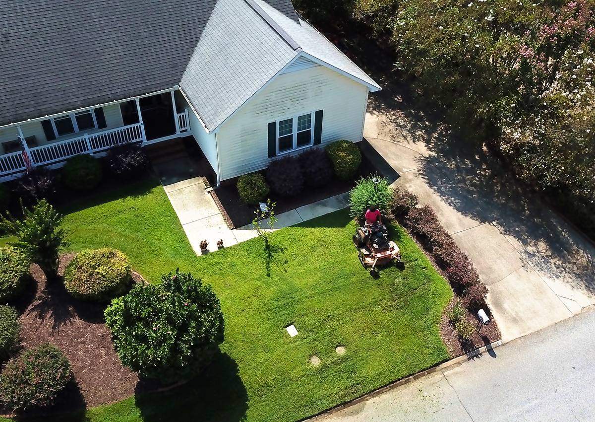 Mowing a landscaped front yard, seen from above.