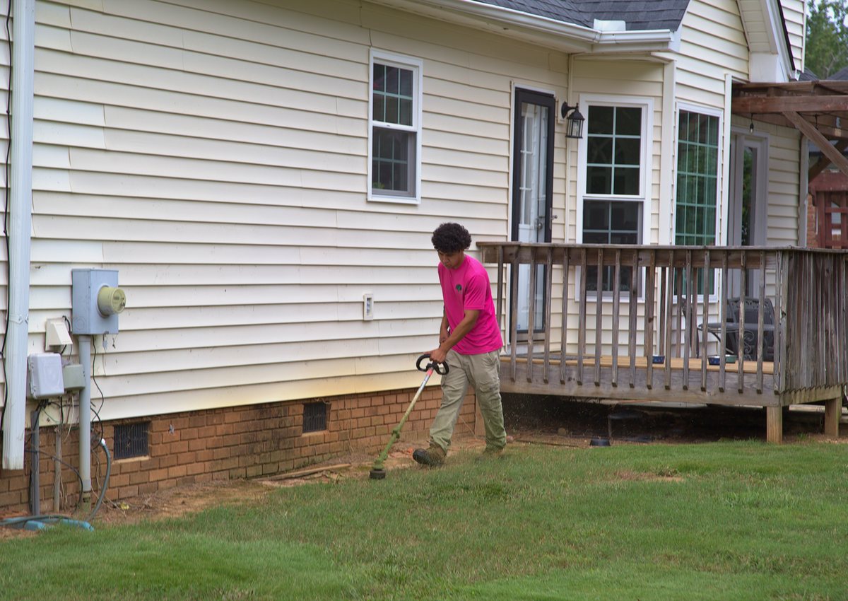 Trimming along the foundation of a house.
