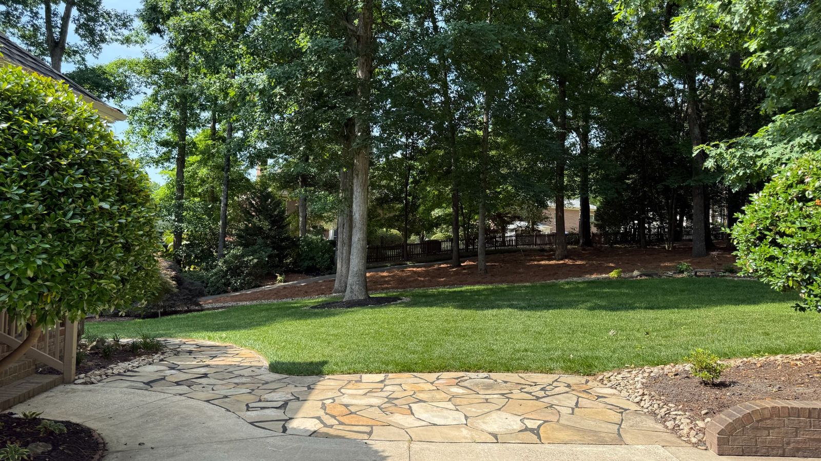 A flagstone walkway curving across a shaded back lawn.