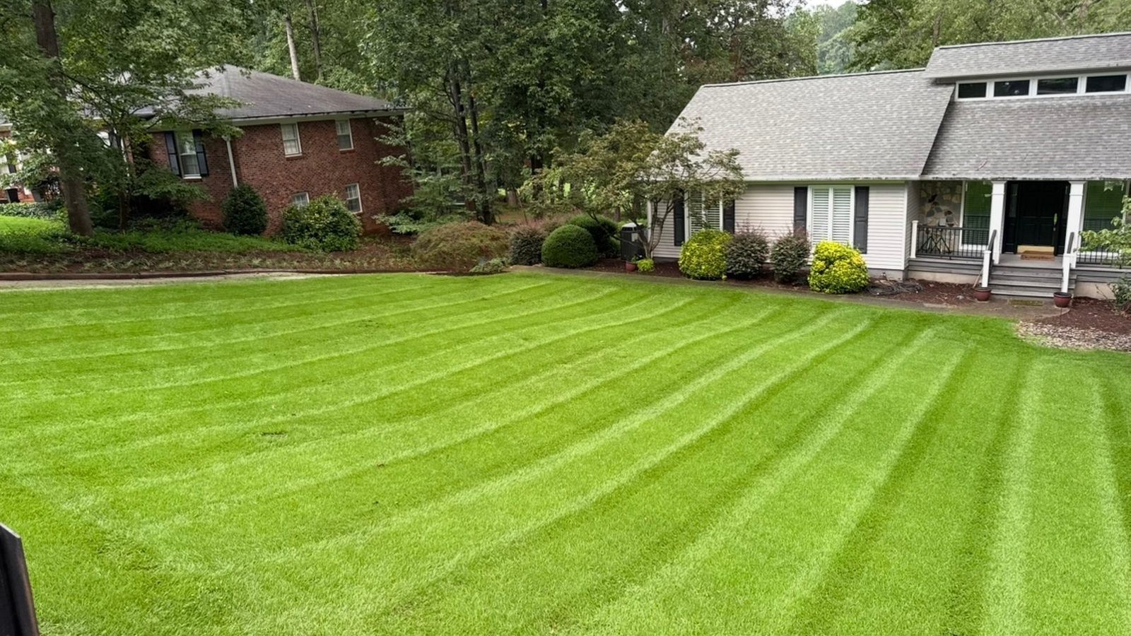 A freshly mowed lawn with clean mowing stripes running up to a brick home.