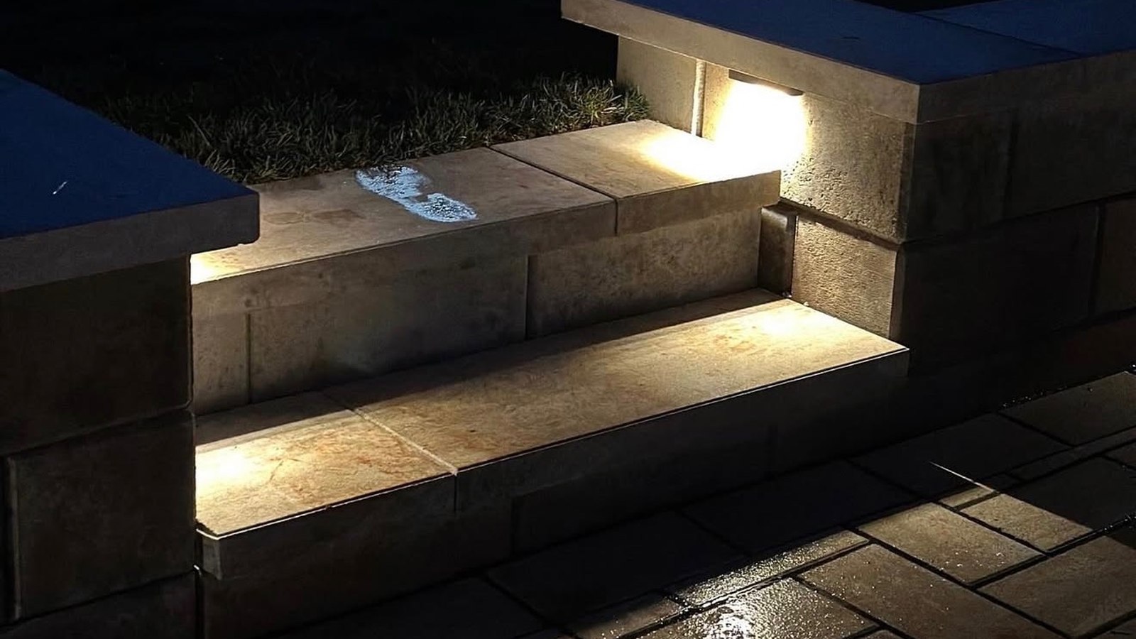 Low-voltage lights washing down a set of paver steps at night.