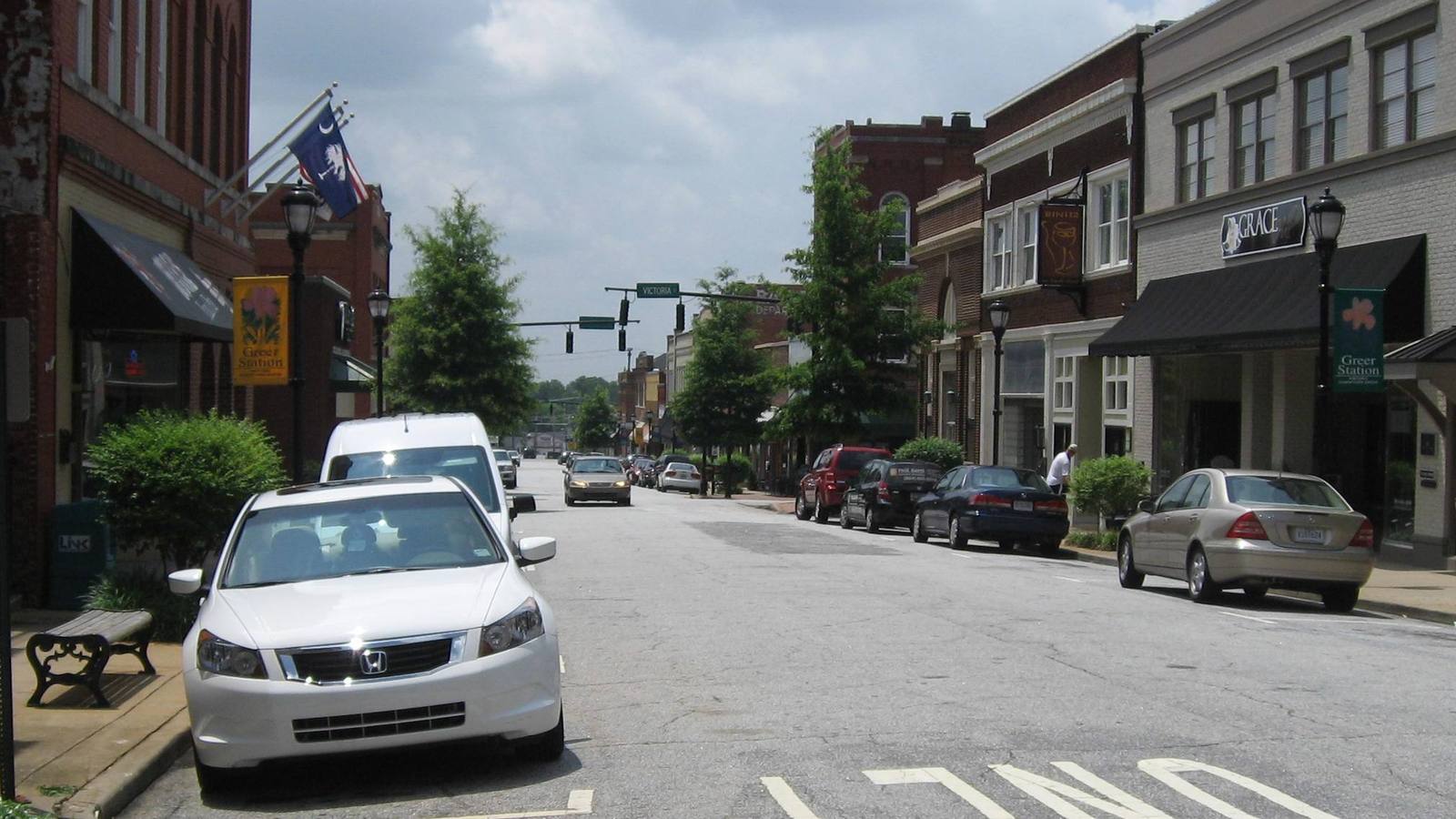 Trade Street in downtown Greer, South Carolina, with storefronts and street parking.